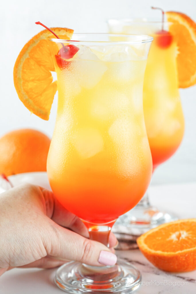hand holding an orange drink