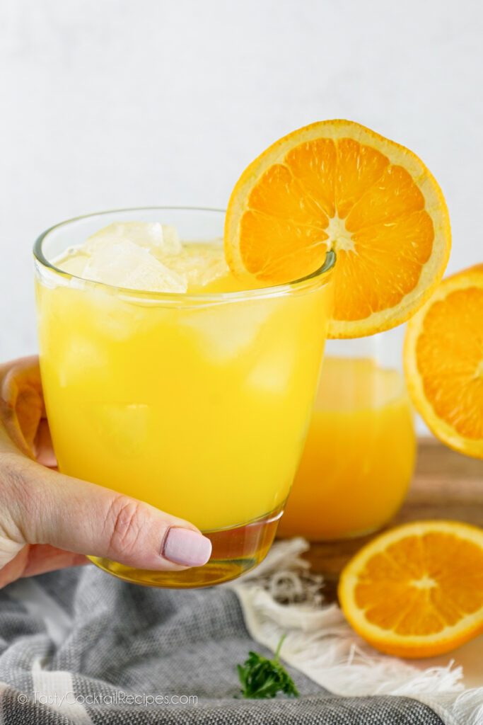 hand holding an orange cocktail
