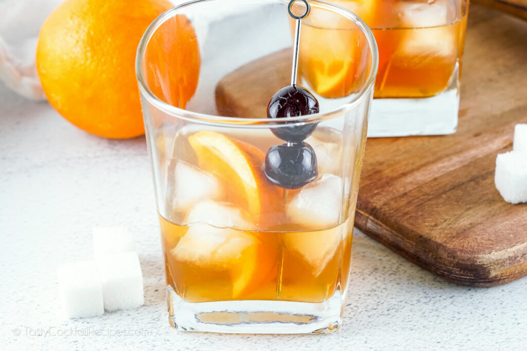 Old Fashioned in cocktail glass with orange and cherries