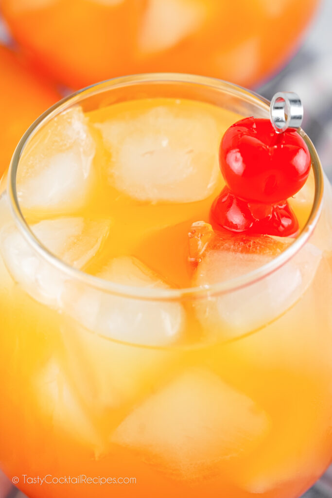 Close up view of an orange and red cocktail with cherries