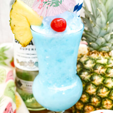 frozen blue cocktail with pineapple and bottle of rum in background