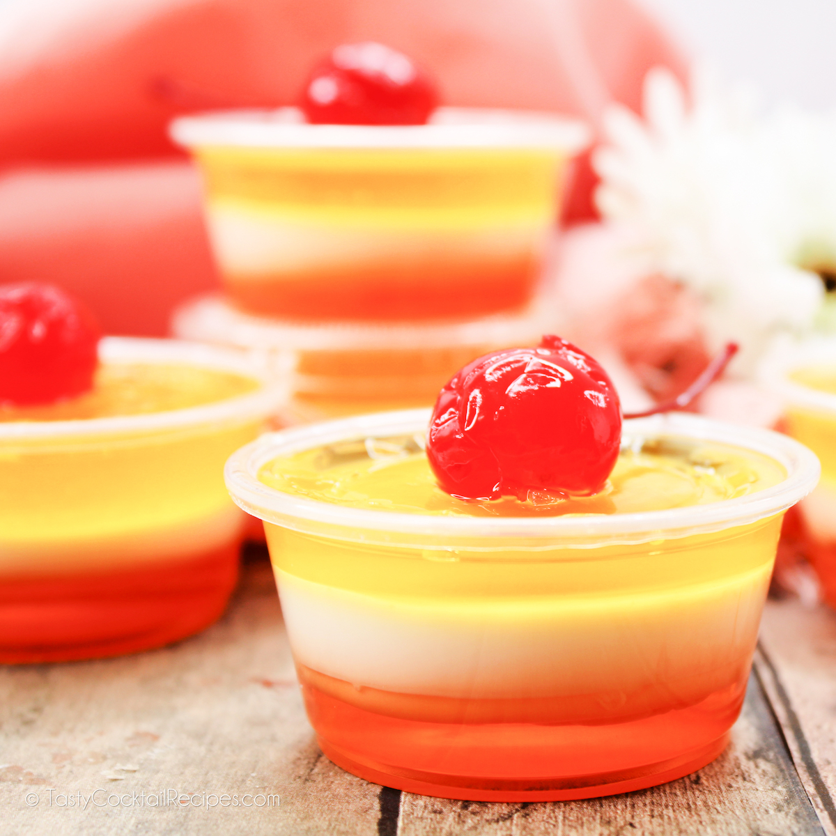 Piña Colada Jello Shots, colored like a sunset, with a cherry on top